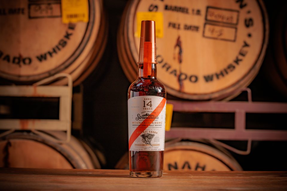Stranahans Mountain Angel 14 Year bottle in front of whiskey barrels